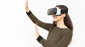 Mujer utilizando gafas de realidad virtual con las manos levantadas.