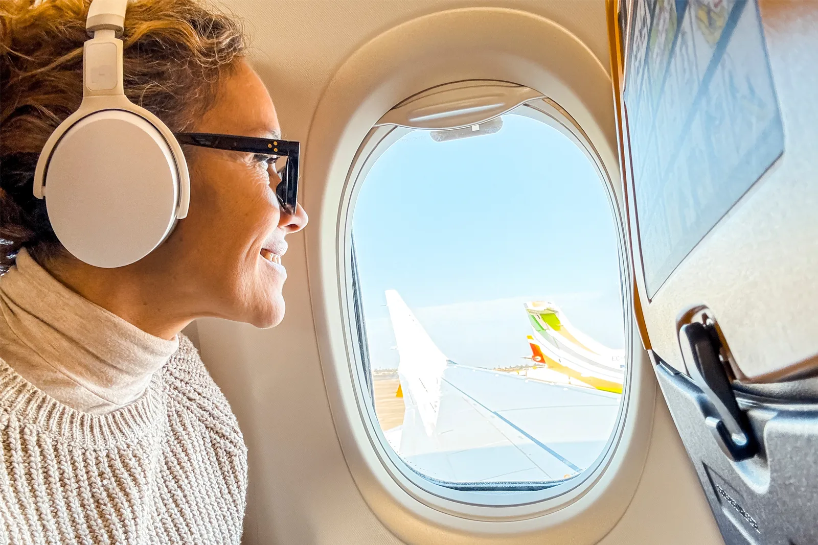 Mujer con auriculares mirando por la ventanilla de un avión